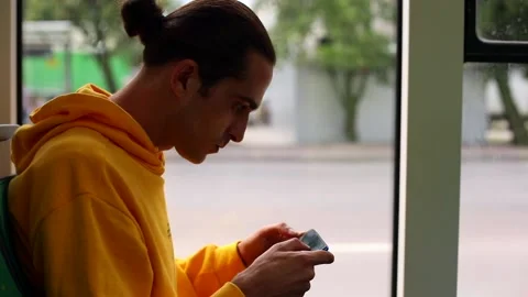 Side view of young man playing game on smartphone mobile while riding by bus Stockbeeldmateriaal 135453860