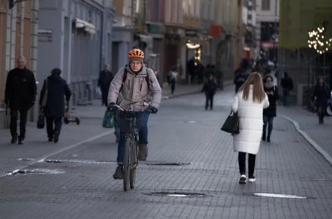 Side view of young man in protective gear with backpack riding bicycle on str Stock Photos