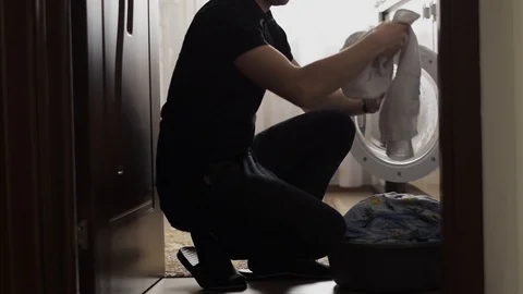 Side View Of Young Man Pulling Out Clothes From Washing Machine Stock Footage 106156270