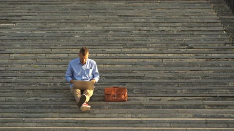 Side View of Young Man Sitting On The Stairs In Park Using Laptop Stock Footage 68067155