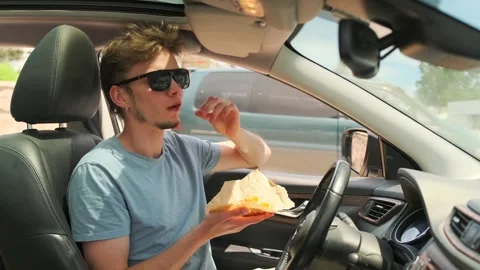 Side view of young man sitting in a car eating french fries Stock Footage 279435518