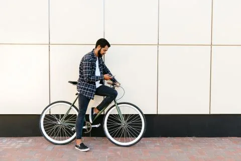 Side view of young man sitting on bike with smartphone, outdoors Stock Photos