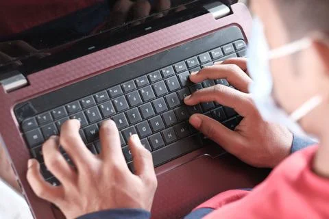 Side view of young man in surgical mask using laptop at home Stock Photos
