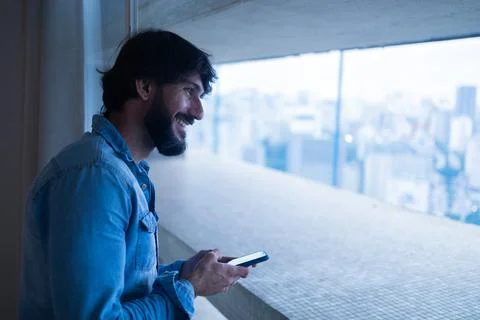 Side view of young man using a smartphone with city view landscape in the bac Stock Photos