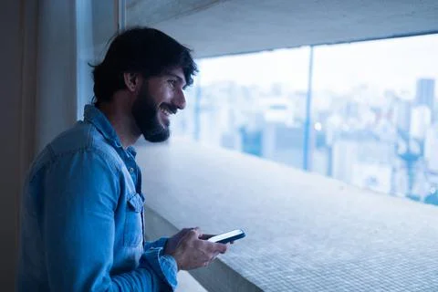 Side view of young man using a smartphone with city view landscape in the bac Stock Photos