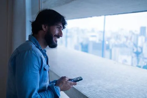 Side view of young man using a smartphone with city view landscape in the bac Stock Photos