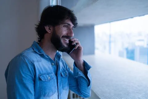 Side view of young man using a smartphone with city view landscape in the bac Stock Photos