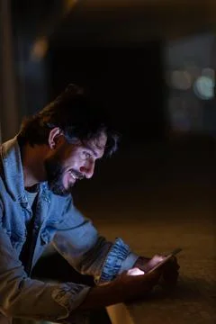 Side view of young man using a smartphone at night time with city view landsc Stock Photos