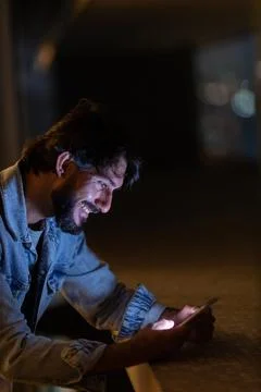 Side view of young man using a smartphone at night time with city view landsc Stock Photos