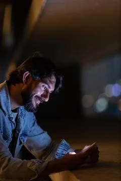 Side view of young man using a smartphone at night time with city view landsc Stock Photos