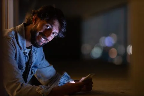 Side view of young man using a smartphone at night time with city view landsc Stock Photos