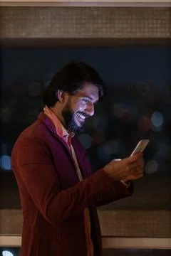 Side view of young man using a smartphone at night time with city view landsc Stock Photos