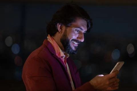 Side view of young man using a smartphone at night time with city view landsc Stock Photos