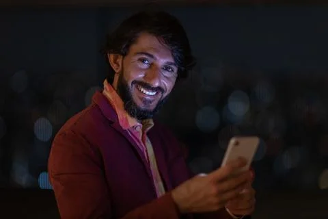 Side view of young man using a smartphone at night time with city view landsc Stock Photos