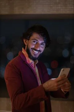 Side view of young man using a smartphone at night time with city view landsc Stock Photos