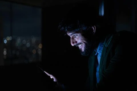 Side view of young man using a smartphone at night time with city view landsc Stock Photos