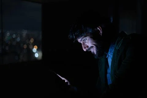 Side view of young man using a smartphone at night time with city view landsc Stock Photos