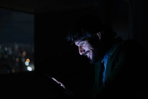 Side view of young man using a smartphone at night time with city view landsc Stock Photos