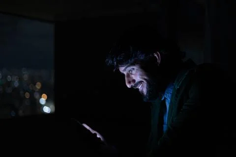 Side view of young man using a smartphone at night time with city view landsc Stock Photos