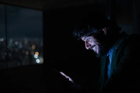 Side view of young man using a smartphone at night time with city view landsc Stock Photos