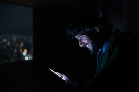 Side view of young man using a smartphone at night time with city view landsc Stock Photos