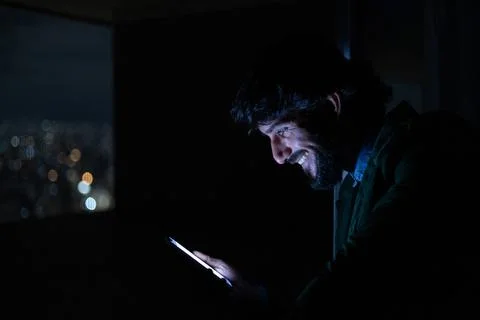 Side view of young man using a smartphone at night time with city view landsc Stock Photos
