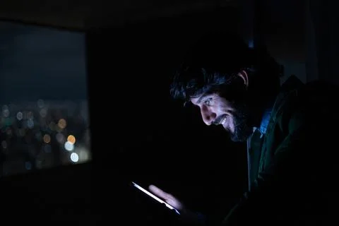 Side view of young man using a smartphone at night time with city view landsc Stock Photos