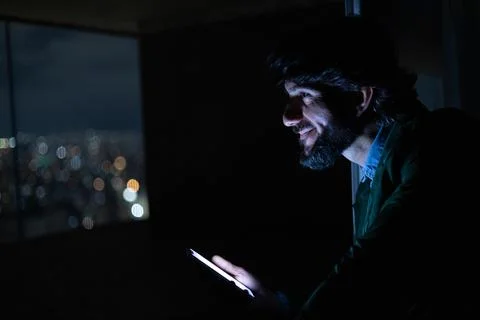 Side view of young man using a smartphone at night time with city view landsc Stock Photos