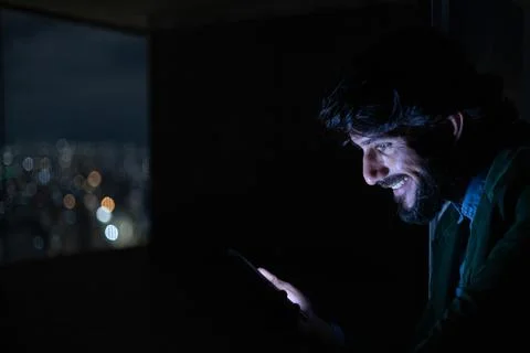 Side view of young man using a smartphone at night time with city view landsc Stock Photos