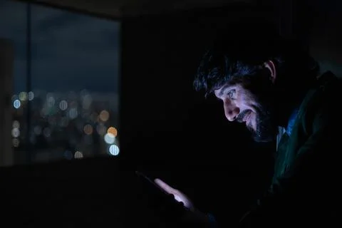 Side view of young man using a smartphone at night time with city view landsc Stock Photos