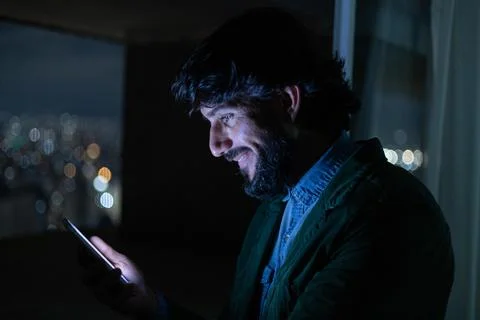 Side view of young man using a smartphone at night time with city view landsc Stock Photos
