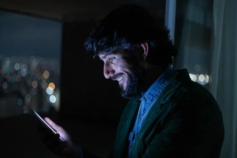 Side view of young man using a smartphone at night time with city view landsc Stock Photos