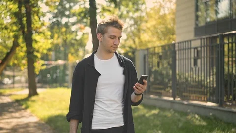 Side view of young man walking and texting Stock-Footage 98306996