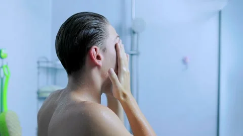 Side view of a young man washing his face under the daily home shower. Stock Footage 345530984