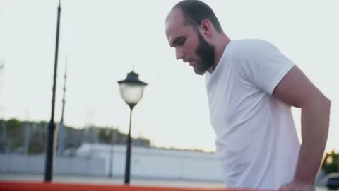 Side view of young man in white t-shirt is pulling up on horizontal bar while Stock Footage 143503101