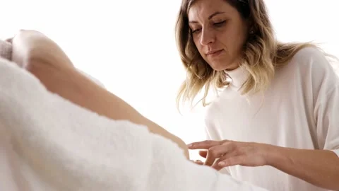 Side view of young masseuse massaging face of young woman lying on sofa Stock Footage 238943040