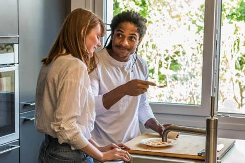 Side view of young multiethnic couple cooking and looking at each other Stock Photos