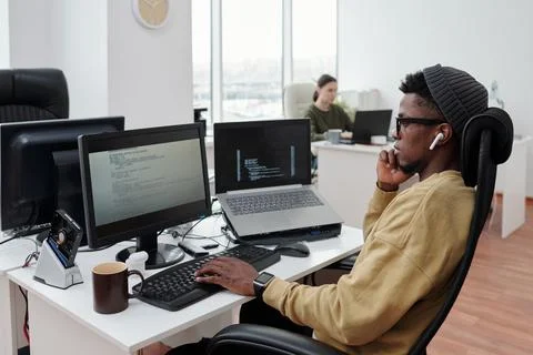 Side view of young serious lack man concentrating on decoding data in office Stock Photos