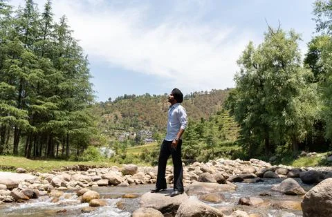 Side View of Young Sikh Man in Formal Clothing Looking Away on River Rocks .. Stock Photos