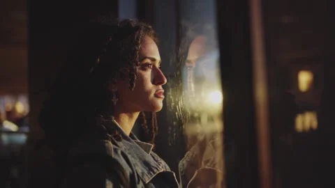 Side view of a young Spanish sad woman looking out the window under bright Stock Footage 157863246