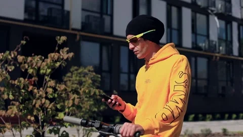 Side view of young sport man in sunglasses and electric scooter using smartphone 스톡 동영상 211723738
