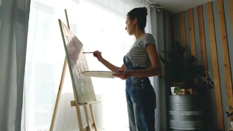 Side view of a young talented charming artist paints an oil picture Stock Footage 111033724