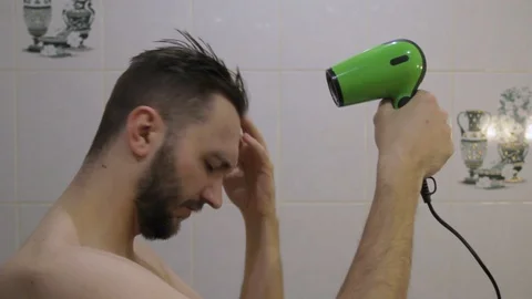 Side view of young undressed man drying hair with hair dryer, singing with dryer Stock-Footage 104022244
