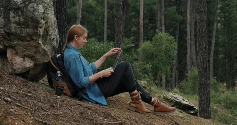 Side view young woman backpacker in forest with laptop sitting by a rock. Stock Footage 151857952