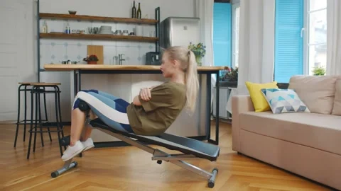 Side view of young woman doing work out on exercise bench at home Stock Footage 132397304