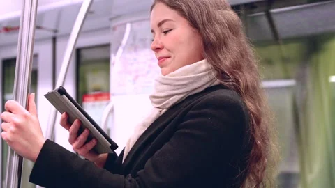 Side view Young Woman Reading on E-Reader While Commuting on Subway Stock Footage 303497437