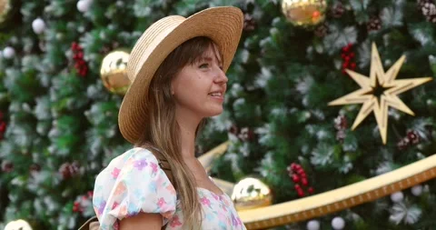 Side view of a young woman in a straw hat standing near a Christmas Stock Footage 293003175
