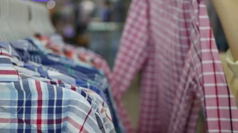 Side view of young woman's hand choosing shirts in store Stock Footage 81620760