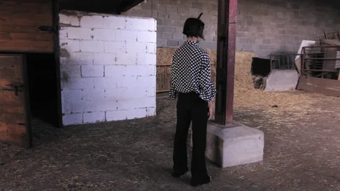 Side view of Zombie female in a barn with a knife stuck on her head. Stock-Footage 117470577