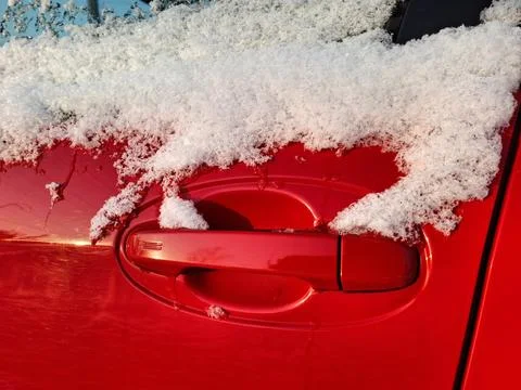 The side window and door handle of the red car are covered with snow Photos
